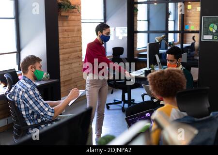 Diverse group of colleagues wearing masks having casual meeting in creative office Stock Photo