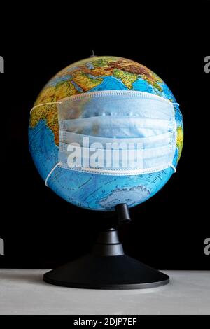 Earth globe in sterile medical mask at the table Stock Photo