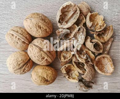 Five whole walnuts and nutshell on a wooden table Stock Photo
