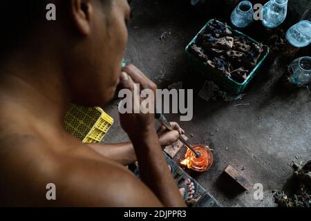 TEGALALANG/BALI-4 DEC 2020: A glazier is shaping hot glass which is done by blowing. Glass crafts in Ubud Bali became a favorite during the COVID-19 p Stock Photo