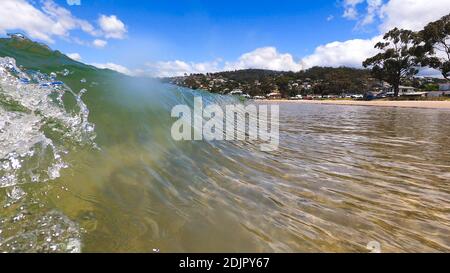 HOBART, TASMANIA - December 6th, 2020: waves crashing at the beach in the popular suburb of Kingston Beach in Suthern Tasmania on a sunny summer day Stock Photo