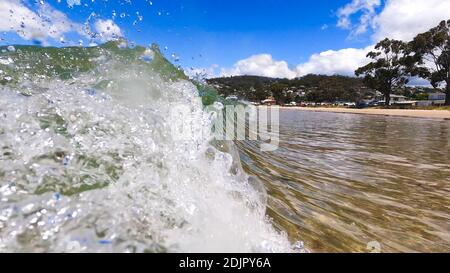 HOBART, TASMANIA - December 6th, 2020: waves crashing at the beach in the popular suburb of Kingston Beach in Suthern Tasmania on a sunny summer day Stock Photo