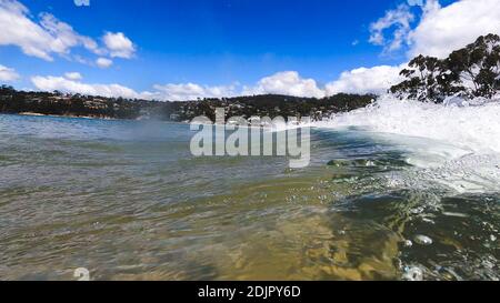 HOBART, TASMANIA - December 6th, 2020: waves crashing at the beach in the popular suburb of Kingston Beach in Suthern Tasmania on a sunny summer day Stock Photo