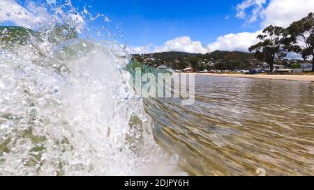 HOBART, TASMANIA - December 6th, 2020: waves crashing at the beach in the popular suburb of Kingston Beach in Suthern Tasmania on a sunny summer day Stock Photo