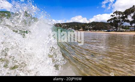 HOBART, TASMANIA - December 6th, 2020: waves crashing at the beach in the popular suburb of Kingston Beach in Suthern Tasmania on a sunny summer day Stock Photo