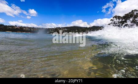 HOBART, TASMANIA - December 6th, 2020: waves crashing at the beach in the popular suburb of Kingston Beach in Suthern Tasmania on a sunny summer day Stock Photo