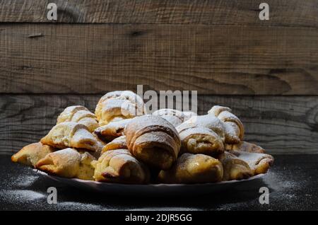 Homemade cookies in the form of bagels with jam filling sprinkled with powdered sugar on a wooden background. Selective focus. Stock Photo