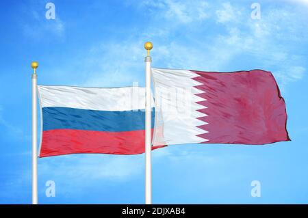 Russia and Qatar two flags on flagpoles and blue cloudy sky Stock Photo