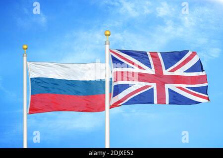 Russia and United Kingdom two flags on flagpoles and blue cloudy sky Stock Photo