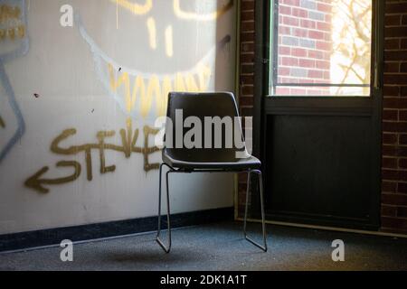 An Empty Chair Next to a Window in a Corner in an Abandoned Building Stock Photo