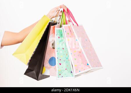 Closeup women hand holding colorful multicolor shopping bag many packets isolated on white background, female holds in hand white clear empty blank cr Stock Photo