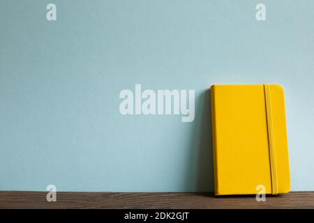 Yellow diary note book on wooden desk. sky blue background Stock Photo