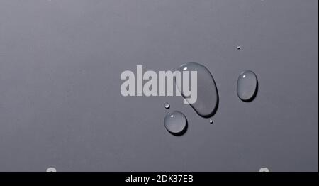 A top view closeup of multiple water drops on a grey background Stock Photo