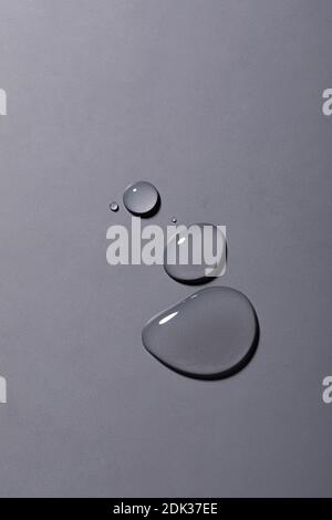 A top view closeup of multiple water drops on a grey background Stock Photo
