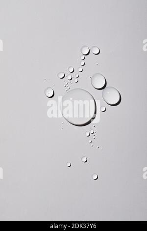 A top view closeup of multiple water drops on a light grey background Stock Photo