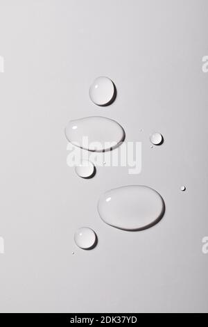 A top view closeup of multiple water drops on a light grey background Stock Photo