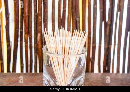 A sel shot of toothpicks in a shot glass, on a wooden surface Stock Photo