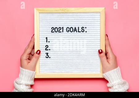 female hands holds felt board with text - 2021 goals on pink background Planning, self motivation, achievement, success, wish list, checklist concept Stock Photo