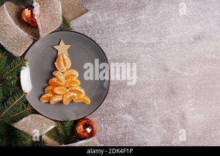 Christmas decorations and fir tree made from tangerines on plate, gray background with copy space Stock Photo