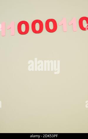 A vertical of red and pink binary codes on a white surface Stock Photo