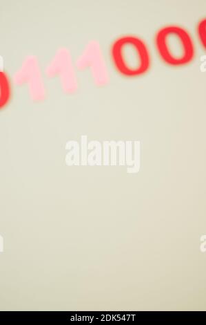 A vertical of blurry red and pink binary codes on a white surface Stock Photo