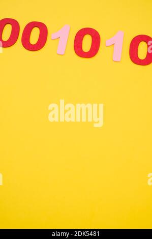 A vertical shotof red and pink binary codes on a bright yellow surface Stock Photo