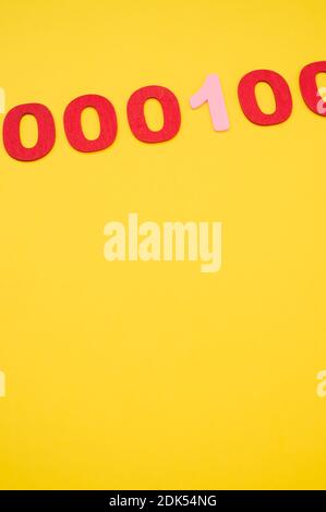A vertical shot of red and pink binary codes on a bright yellow surface Stock Photo