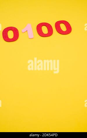 A vertical shot of red and pink binary codes on a bright yellow surface Stock Photo