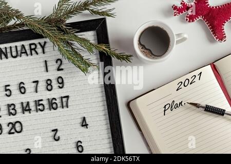 Notepad for taking notes of goals and plans for the new year, calendar,a cup of coffee, Christmas tree decorations on the desktop.Inscription in Engli Stock Photo
