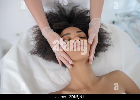 Face of young pretty girl and hands of beautician Stock Photo