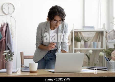 Interested lady designer standing by computer screen creating new sketch Stock Photo