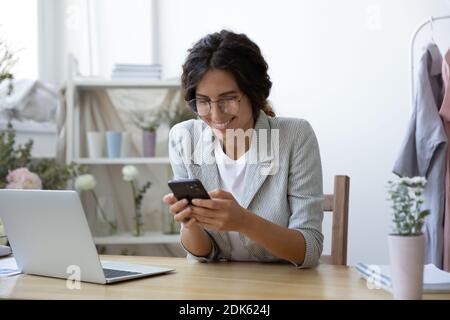 Excited young female clothing designer reading email with profitable offer Stock Photo