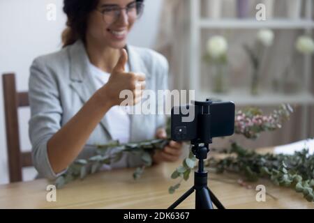 Female florist working at home recording making bouquet on webcam Stock Photo