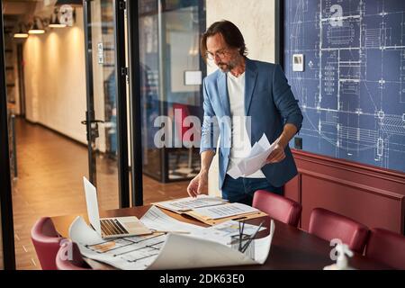 Brunette bearded man in blazer sorting out papers in class Stock Photo