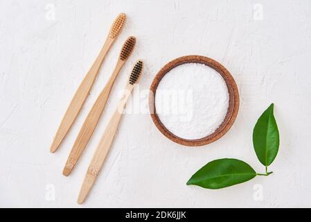 Three wooden bamboo toothbrushes and baking soda on a white background, top view. Eco friendly toothbrushes, zero waste concept Stock Photo