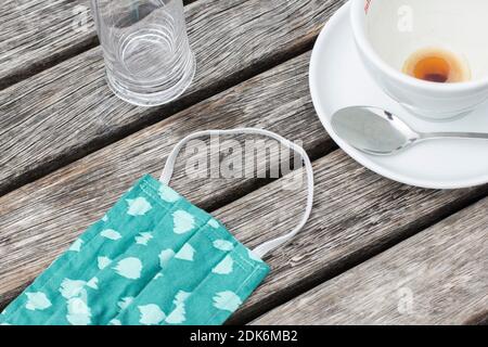 Empty coffee cup and mouth and nose mask on a wooden table Stock Photo