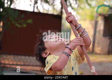 A little child holding a wooden stick and looking at it Stock Photo