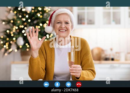 Positive mature lady in Santa hat celebrating New Year Stock Photo