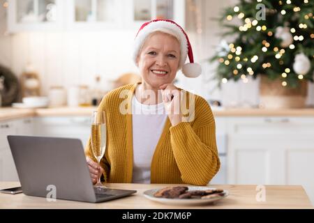 Elegant old woman in Santa hat using laptop Stock Photo
