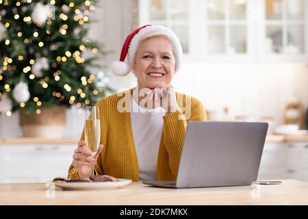 Beautiful granny in Santa hat sitting in front of laptop Stock Photo