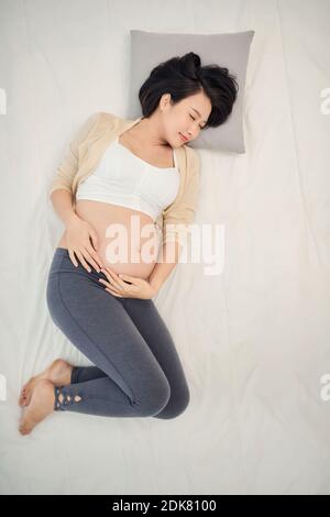 Young pregnant woman sleeping on maternity pillow in bed Stock Photo