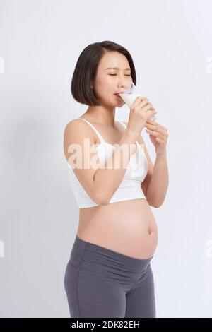 Pregnant woman drinking milk on the white background. Stock Photo