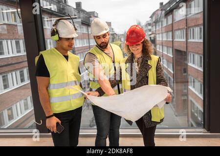 Workers reviewing blueprint at construction site Stock Photo