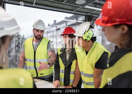 Workers reviewing blueprint at construction site Stock Photo