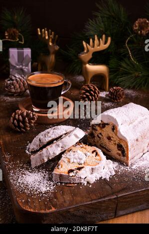Sweet bread with dry dried fruits for Christmas. Stollen and aromatic espresso coffee with gift boxes on a wooden background. Copy space. High quality photo. Stock Photo