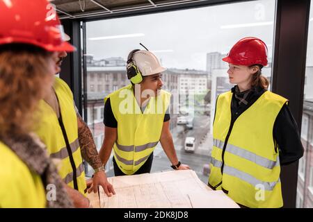 Workers reviewing blueprint at construction site Stock Photo