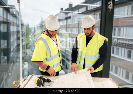 Workers reviewing blueprint at construction site Stock Photo