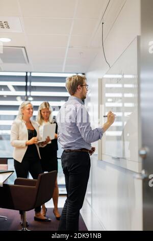Businessman writing on whiteboard in office Stock Photo