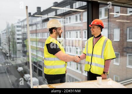 Workers having handshake at construction site Stock Photo
