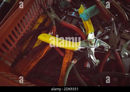 Old pliers in plastic basket. Second-hand tool for sale at tools market. Old pliers in tool tray. Toolkit of handyman. Mechanic hand tools. Used tools Stock Photo